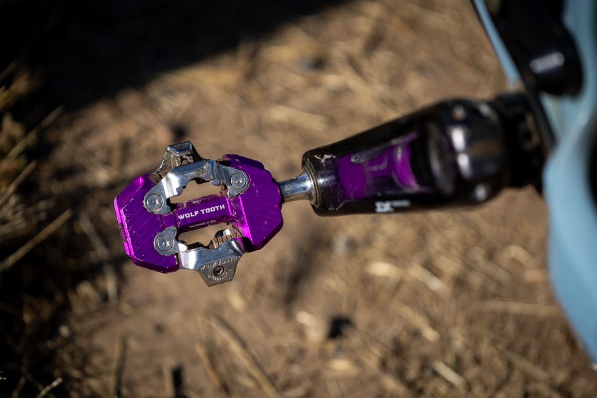 Purple Wolf Tooth CTRL Trail pedal reflected in a crank arm