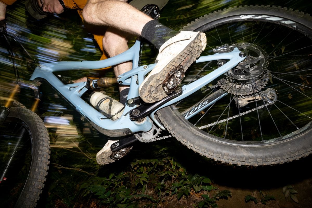 OneUp Components CLIP pedals visible from below as a rider catches air on a jump